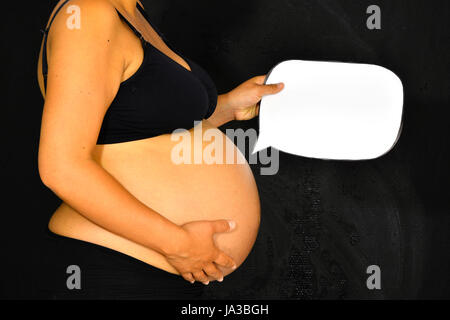 Una donna in stato di gravidanza sta tenendo un discorso bolla per la sua pancia per mostrare ciò che il bambino sta dicendo. Foto Stock