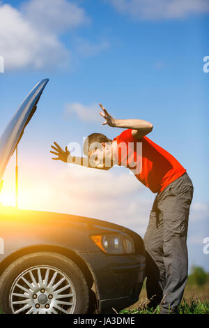 Brunet che guarda alle auto del cofano sulla strada durante il giorno Foto Stock