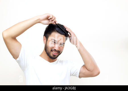 Concetto di persone - sorridente giovane di spazzolare i capelli con il pettine su sfondo bianco Foto Stock