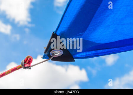 Tende da sole in forma vele su sfondo con cielo nuvoloso. Dettaglio del fissaggio della tenda da sole per il cavo Foto Stock