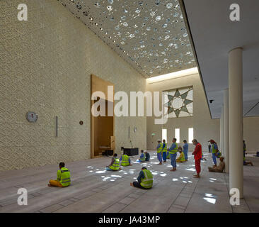 Interno della moschea durante la preghiera con pezzata luce. La Moschea Jumaa, Doha, Emirati Arabi Uniti. Architetto: John McAslan & Partners, 2017. Foto Stock