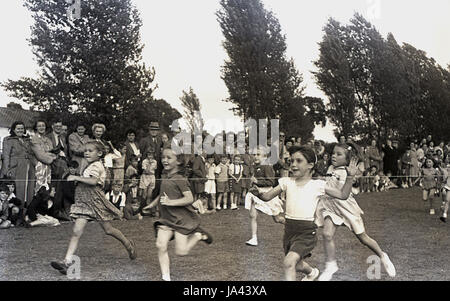 Degli anni Cinquanta, storico, giovani ragazze circa per colpire la finitura di corda in 60 yard dash in una scuola primaria giornata di sport, Inghilterra, Regno Unito. Foto Stock