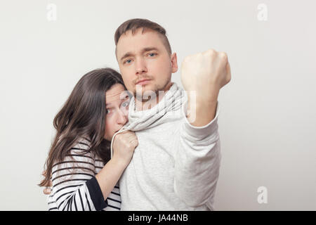 Coraggioso giovane uomo proteggendo la sua ragazza. Egli ha messo il suo pugno in avanti. Ella si nasconde nella paura dietro di lui Foto Stock