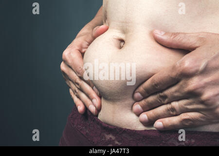 Donna che mantiene in mani Big fat belly Foto Stock
