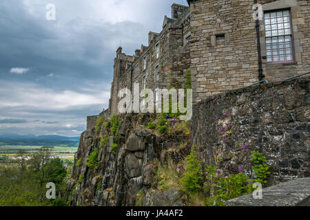 Vista della scogliera rocciosa affioramento con il Castello di Stirling parete e paesaggio distante oltre Carse di Stirling, con moody cielo grigio, Stirling, Scozia, Regno Unito Foto Stock