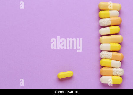 Pillole di colore giallo su sfondo colorato Foto Stock