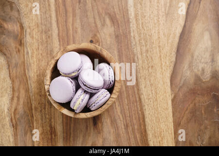 Violetta macarons nella ciotola di legno sul tavolo di legno dal di sopra Foto Stock