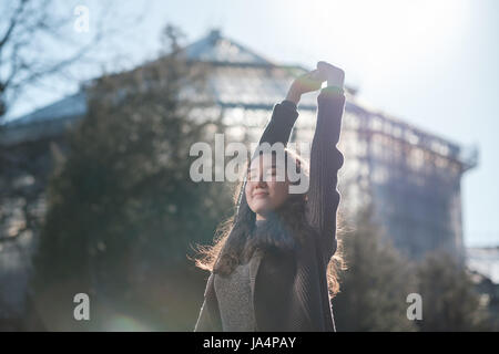 Una bella ragazza asiatica è in piedi nel parco e a riposo crogiolarsi al sole. Godetevi il silenzio nella vita della città. Foto Stock