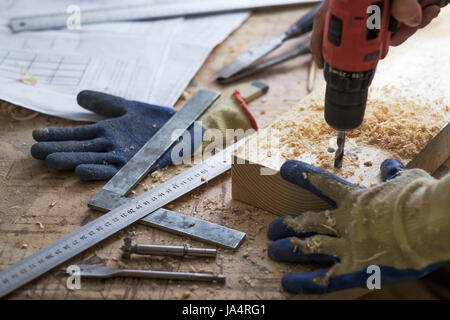 Il carpentiere realizza fori con una punta da trapano in una parte di legno Foto Stock