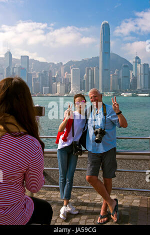 Vista verticale di turisti di scattare le foto del drammatico skyline di Hong Kong Island, Cina. Foto Stock