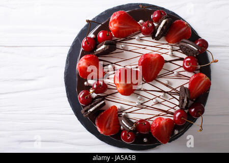 Festosa torta al cioccolato con fragola e ciliegia vicino sul tavolo. vista orizzontale dal di sopra Foto Stock