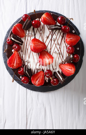 Festosa torta al cioccolato con fragola e ciliegia vicino sul tavolo. vista verticale da sopra Foto Stock