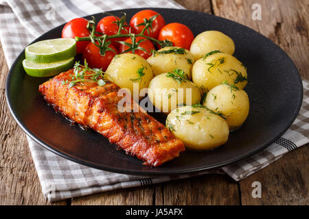 Salmone alla griglia e patate novelle bollite, pomodori freschi di close-up su una piastra orizzontale. Foto Stock