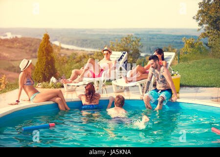 Gruppo giovane godendo in piscina in estate Foto Stock