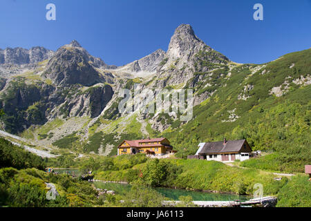 Scenic landscape view of a hut and house in the High Tatras mountains in Slovakia with a high peak in the background in a travel and tourism concept Foto Stock