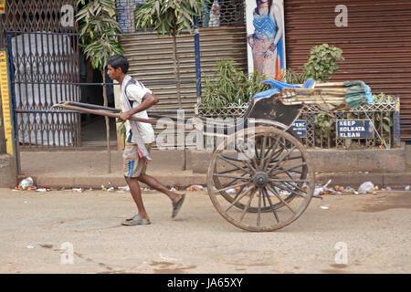 L'uomo tirando a mano tradizionale risciò tirato lungo una strada in Kolkata, West Bengal, India. Foto Stock