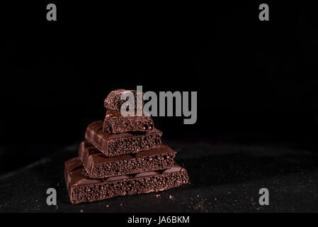 Pila di nero di cioccolato dei pori su sfondo nero Foto Stock