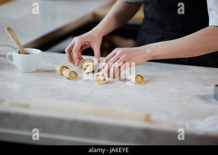 Interni orizzontali crop colpo di mani di donna che lavorano con impastare e formare la pasta in cucina. Foto Stock