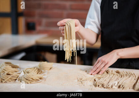 Irriconoscibile cuocere pasta. Interni orizzontali crop colpo di cuocere il lavoro con impastare e preparare gli spaghetti in cafe. Fare la pasta. La produzione di pasta a re Foto Stock