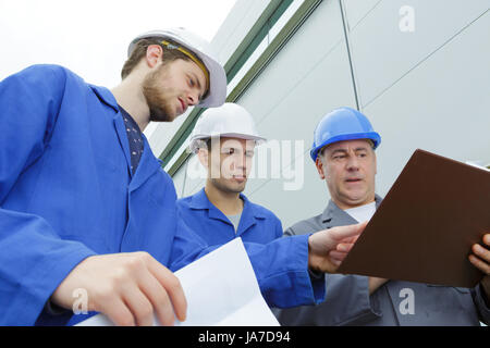 Gruppo di costruttori in hardhats con clipboard Foto Stock