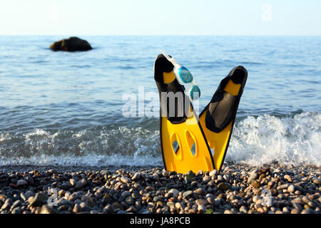 Concetto di immersioni. Coppia di giallo di pinne e occhiali sulla riva del mare con spazio libero per il testo Foto Stock