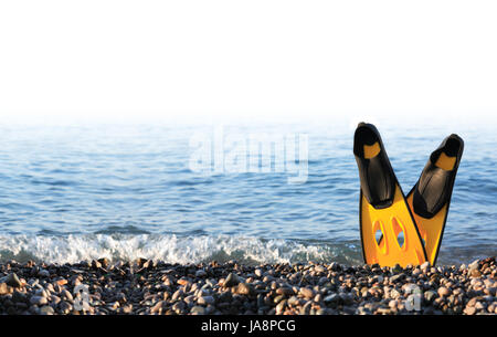 Concetto di immersioni. Coppia di pinne gialle in piedi sulla riva del mare contro il mare Foto Stock