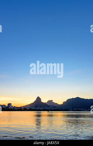 Immagine del tardo pomeriggio alla laguna di Rodrigo de Freitas a Rio de Janeiro con le sue montagne, gli edifici e il profilo caratteristico Foto Stock