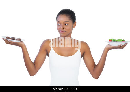 Donna di decidere di mangiare in modo sano o non è su sfondo bianco Foto Stock