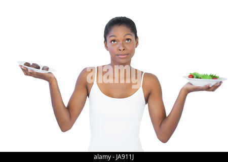 Conflitto donna di decidere di mangiare in modo sano o non è su sfondo bianco Foto Stock