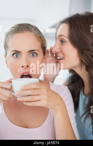 Storditi donna venga detto segreto mentre si beve il caffè Foto Stock