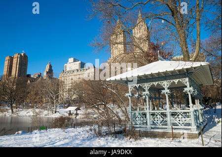 Mattino luminoso in prospettiva di un gazebo panoramico sul bordo del lago ghiacciato a Central Park dopo una tempesta invernale coperto di New York City in snow Foto Stock