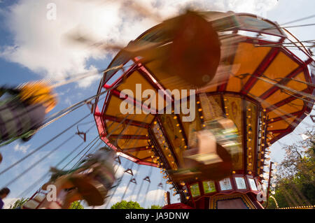 Catena giostra swing ride al carnevale con motion blur durante il tramonto Foto Stock