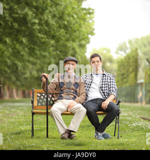 Il nonno con il nipote seduta su una panchina nel parco e guardando la telecamera Foto Stock
