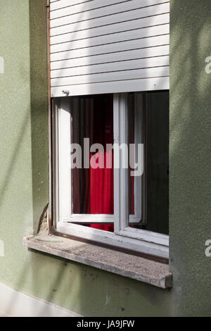 Finestra parzialmente aperto con un sipario rosso. Vista dall'esterno. Foto Stock