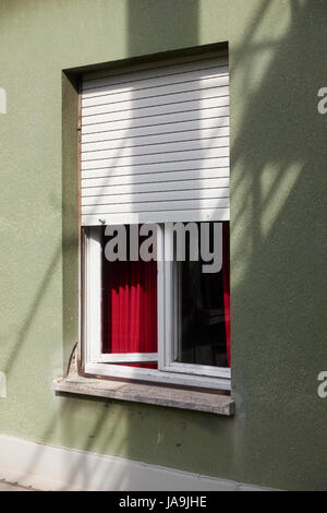 Finestra parzialmente aperto con un sipario rosso. Vista dall'esterno. Foto Stock