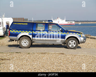 H.M. I guardacoste 4 ruote motrici la visione di attività a Calshot Beach, Southampton, Hampshire, Inghilterra, Regno Unito con Red Funnel in background Foto Stock