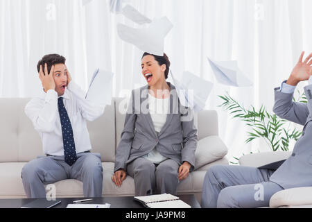 Imprenditori sconvolto al collega urlando e gettando le carte sul divano in office Foto Stock