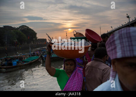 Una donna che porta una ciotola di pesce fresco sul suo capo a Sassoon dock, Mumbai, India. Foto Stock