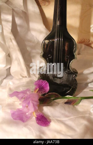 Bottiglia di cristallo con il vino in forma di violino e iris flower un bel decor e il dono Foto Stock