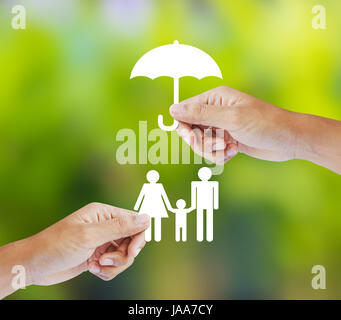 Mano che tiene una carta famiglia e ombrello su sfondo verde Foto Stock