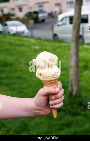 Un bambino di trattenimento di un cono gelato. Foto Stock