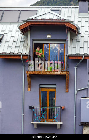 L'uomo in alto balcone che guarda fuori e mangiare Foto Stock