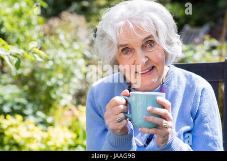 Ritratto di donna Senior relax nel giardino con una bevanda calda Foto Stock