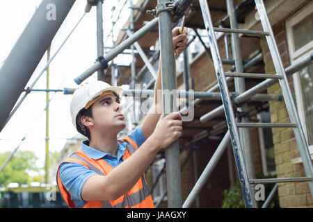 Builder sul sito mettendo su un ponteggio Foto Stock