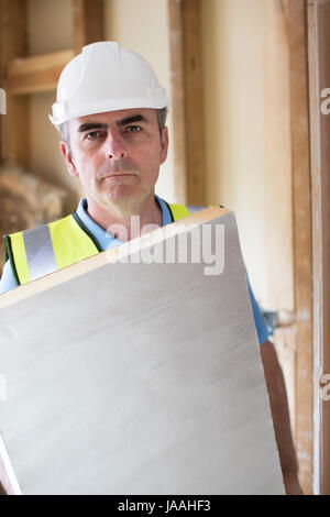 Ritratto di Builder montaggio tavole di isolamento nel tetto della nuova casa Foto Stock