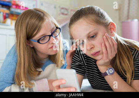 Pre-Teen Ragazza con amico di essere vittima di bullismo mediante messaggio di testo Foto Stock