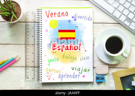 La scrittura a mano su un notebook in una lingua di classe con la parola 'Spanish' scritto su. Disegno a mano di una spiaggia in scena in estate. Alcuni materiale in aula Foto Stock