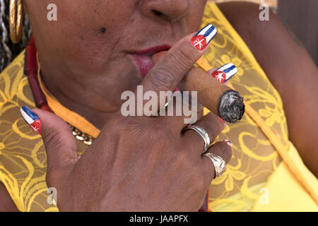 Latina donna fumatori di sigaro Avana, Cuba. Ispanico lady nero e il fumo di tabacco, il folklore dei Caraibi. Primo piano della bocca di soffiaggio e di fumo bandiera cubana p Foto Stock