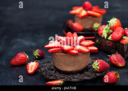 Singoli mini Cheesecake al cioccolato dessert decorate con fragole fresche Foto Stock