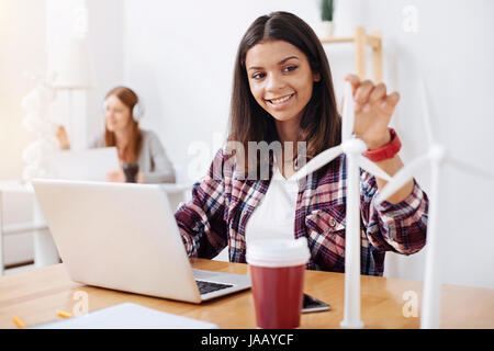 Fonti di energia rinnovabili. Giovani motivati ingegnere professionale seduti in classe e a sviluppare la sua idea circa l'energia eolica mentre facendo alcuni modelli di brillanti Foto Stock